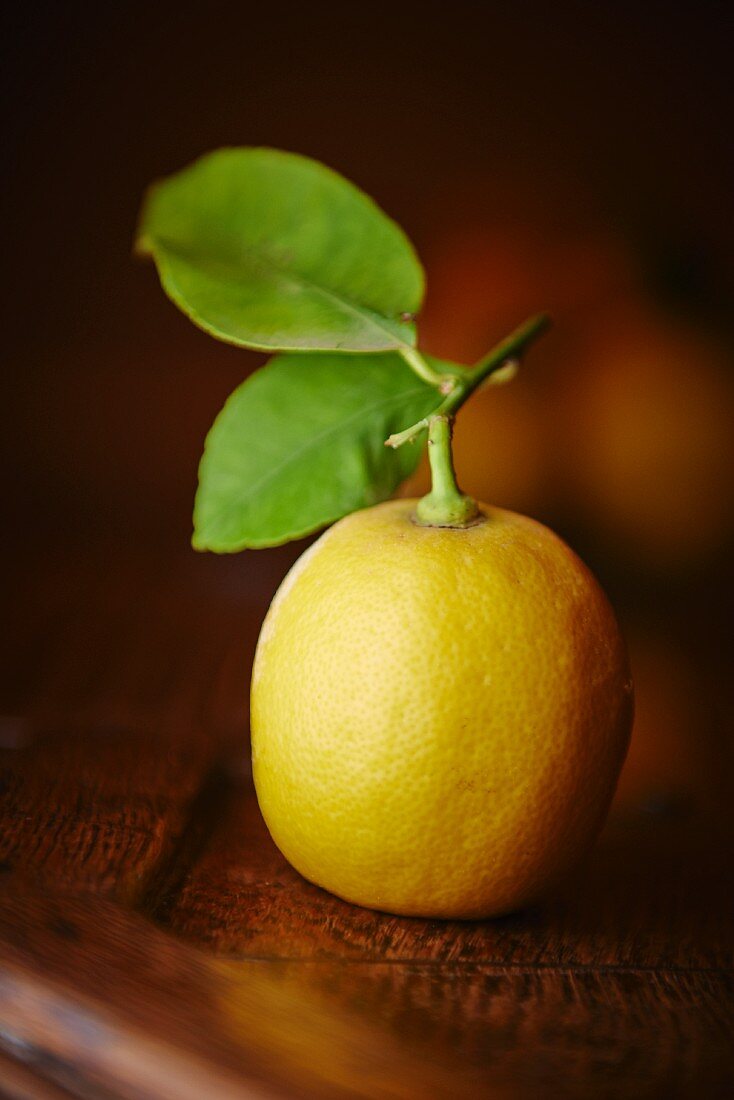 A lemon with a leaf and a stalk
