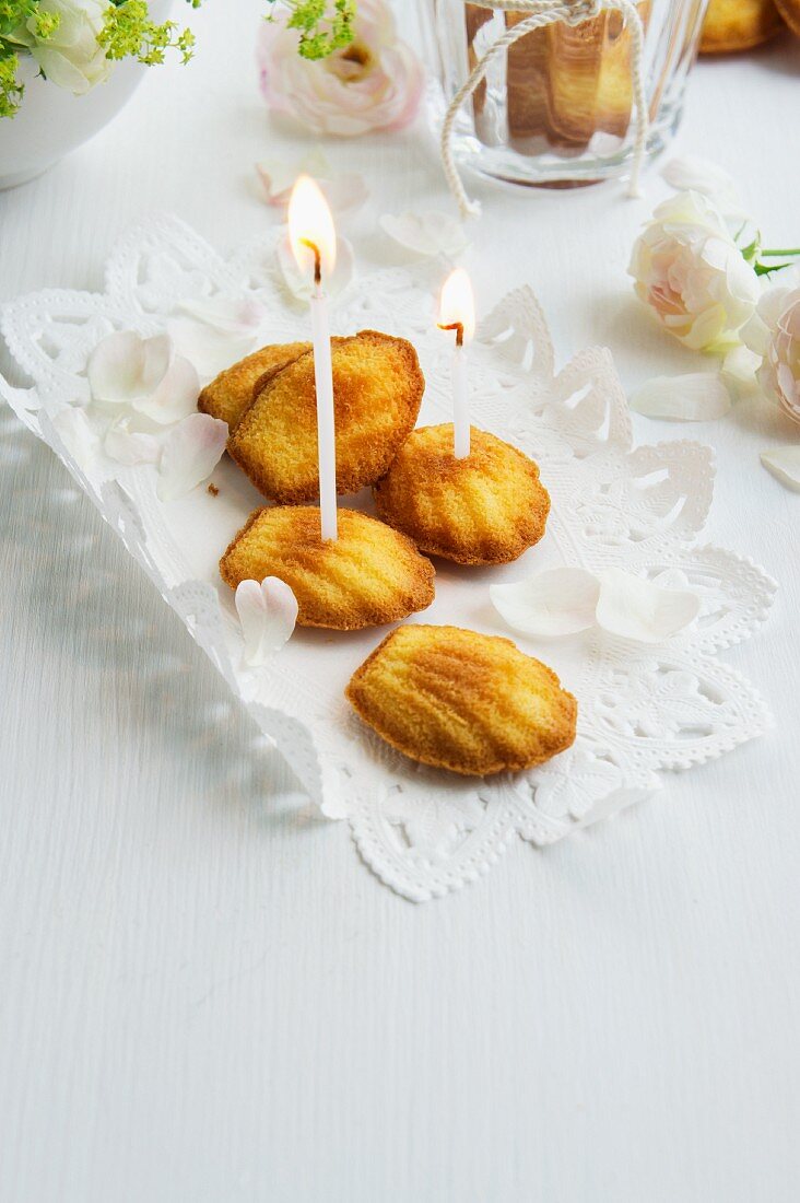 Madeleines auf Tortenspitze mit kleinen Kerzen