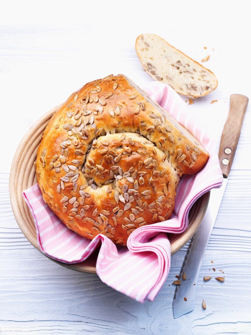 A bread basket holding a loaf of bread made with quark and oil and topped with sunflower seeds