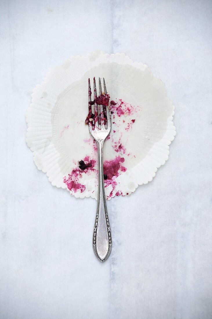 The remains of berry cake on a paper doily