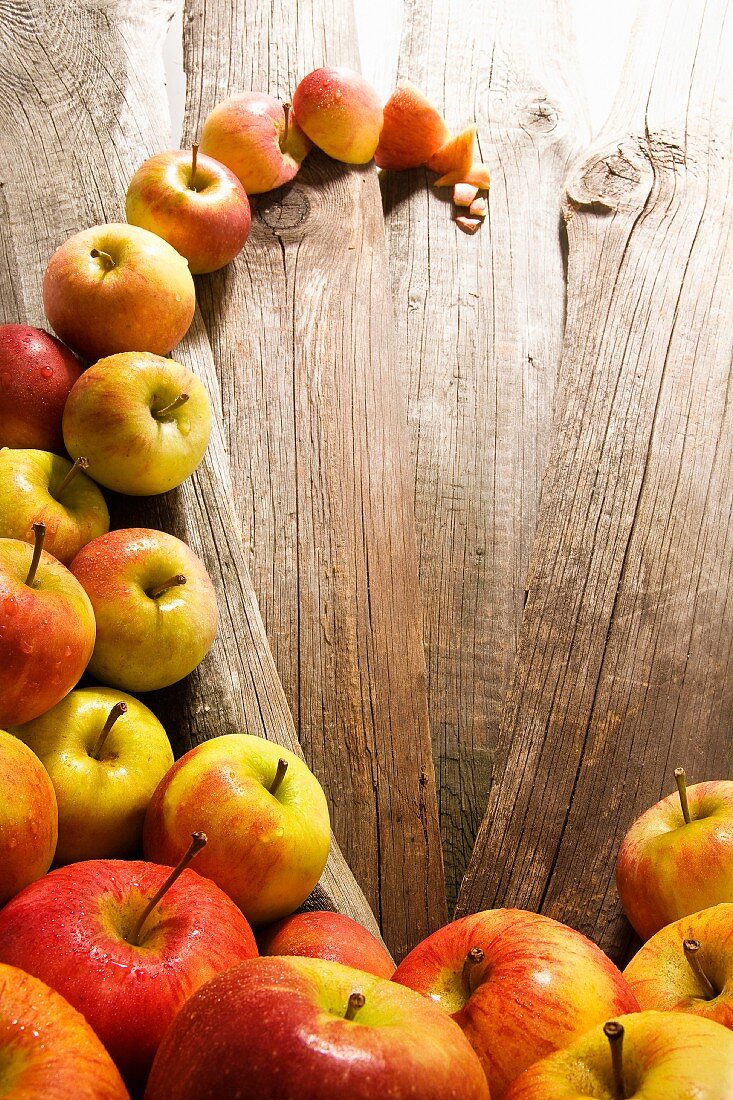 A wave of bedewed apples (Elstar, Jonagold) on rustic wood boards