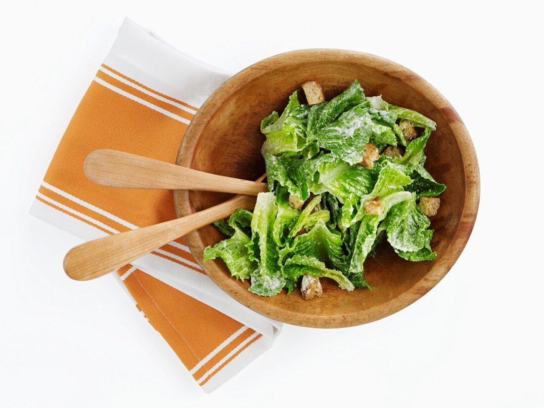 Caesar Salad in einer Holzschüssel mit Salatbesteck