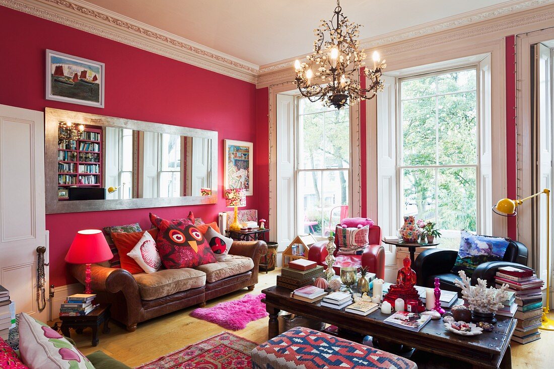 Hot pink walls in grand room with large, long, wall-mounted mirror, leather couch and floor-to-ceiling windows