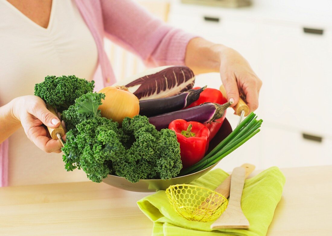 Woman with fresh vegetables in kitchen