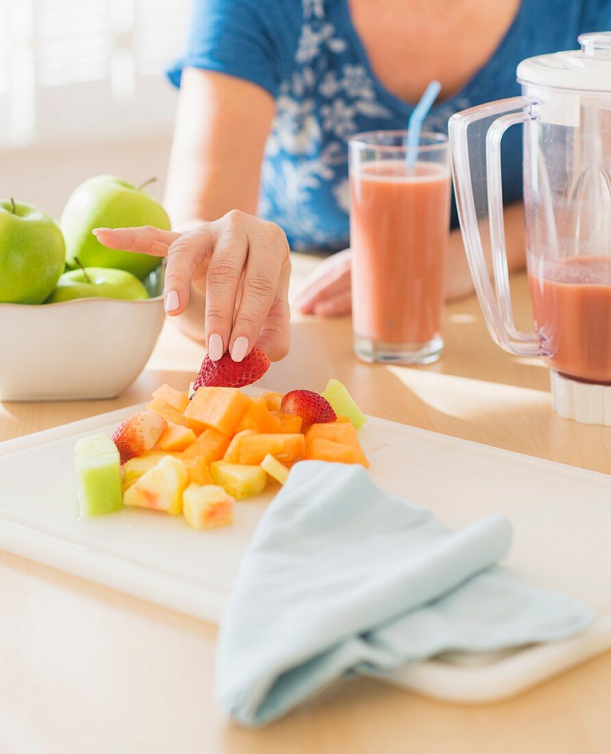 Frau isst Obst in der Küche