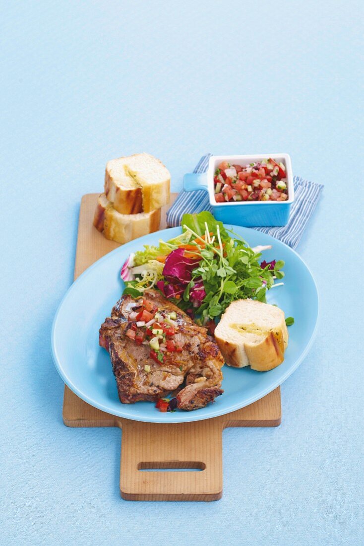 Lamb chop with salsa, salad and chunks of baguette