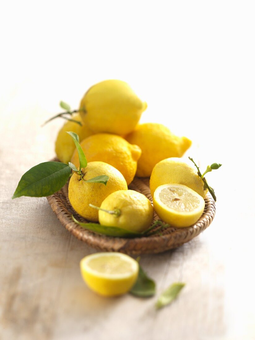 Several lemons, whole and halved, in a basket