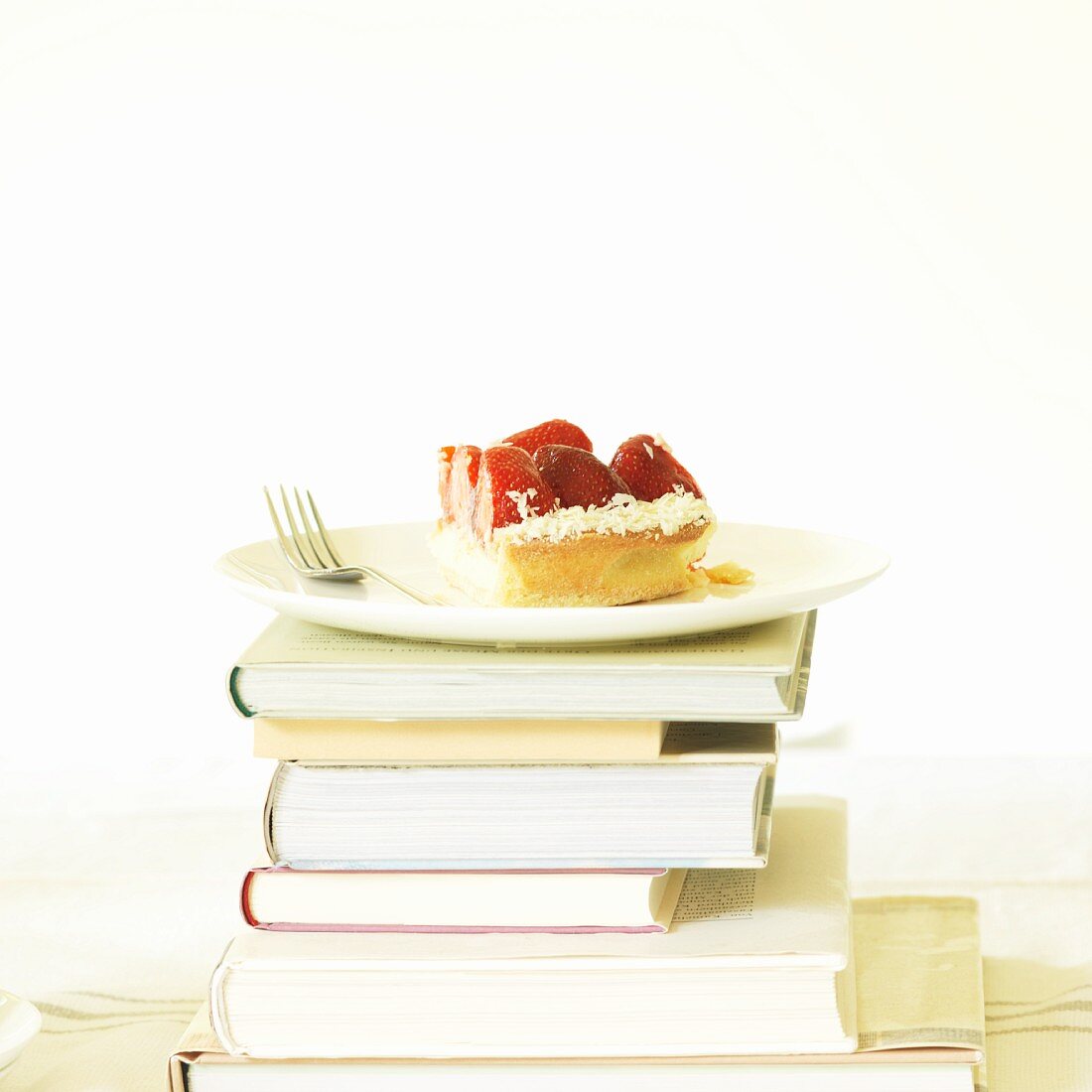 A slice of strawberry cake on a stack of books
