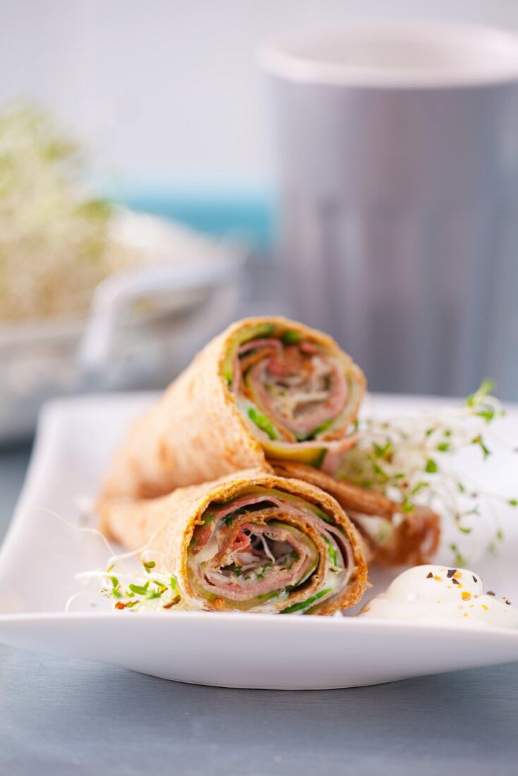 Tortilla wraps cut in half with Parma ham, cucumber, lambs lettuce, sprout and yoghurt dressing