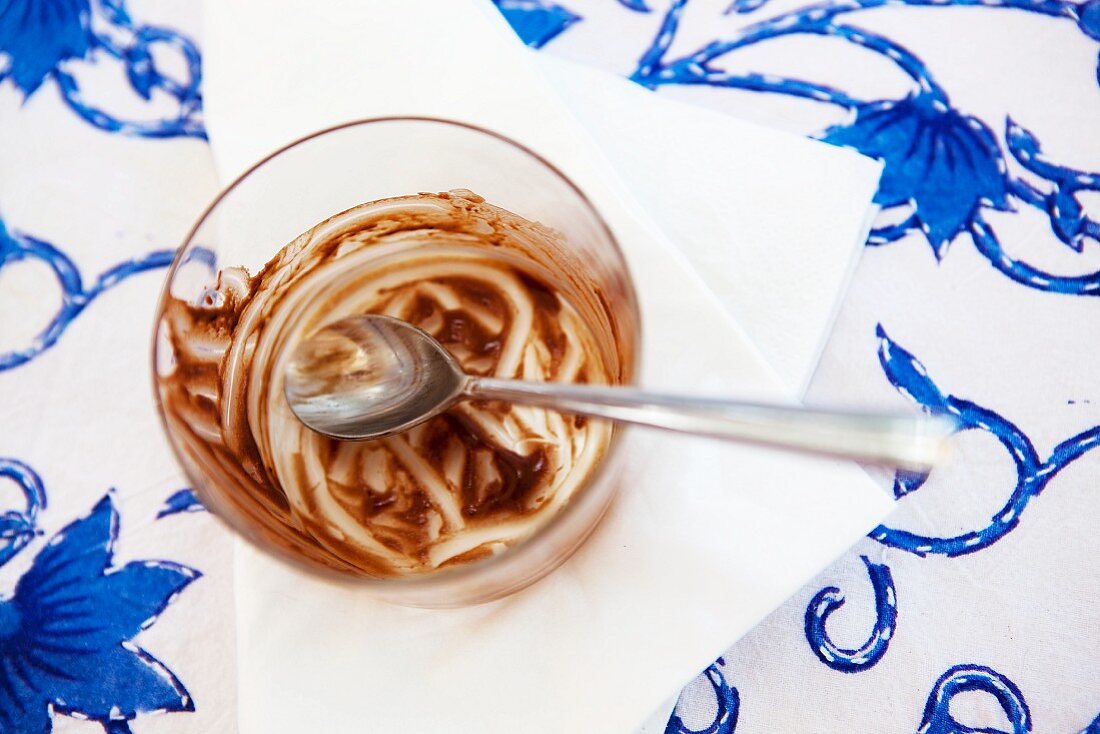 A glass containing the remains of chocolate mousse