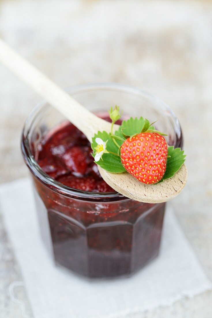 Strawberry jam with a strawberry and a wooden spoon
