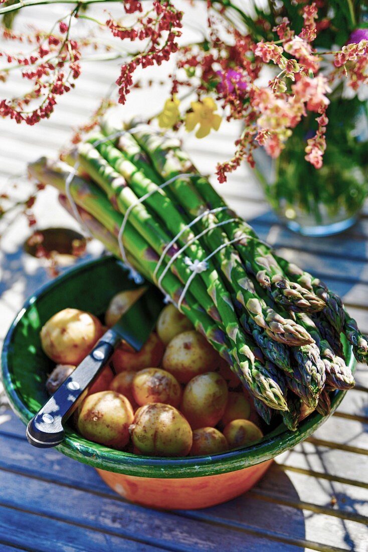 A bunch of asparagus on top of a bowl of potatoes