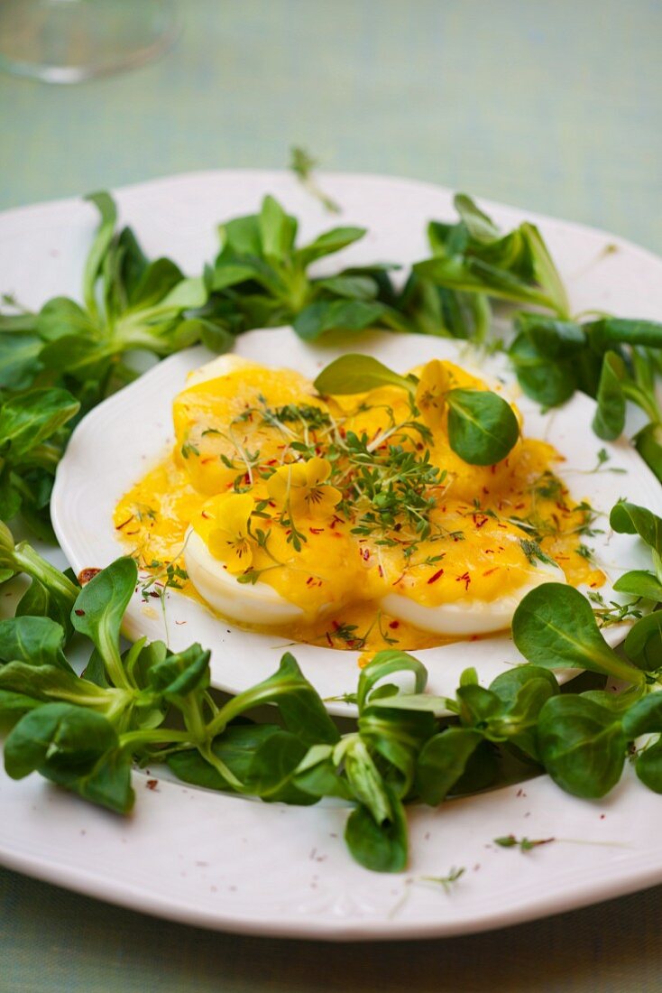 Halbe hartgekochte Eier mit Mayonnaise und Käsesauce, garniert mit Feldsalat, Safran und Kresse