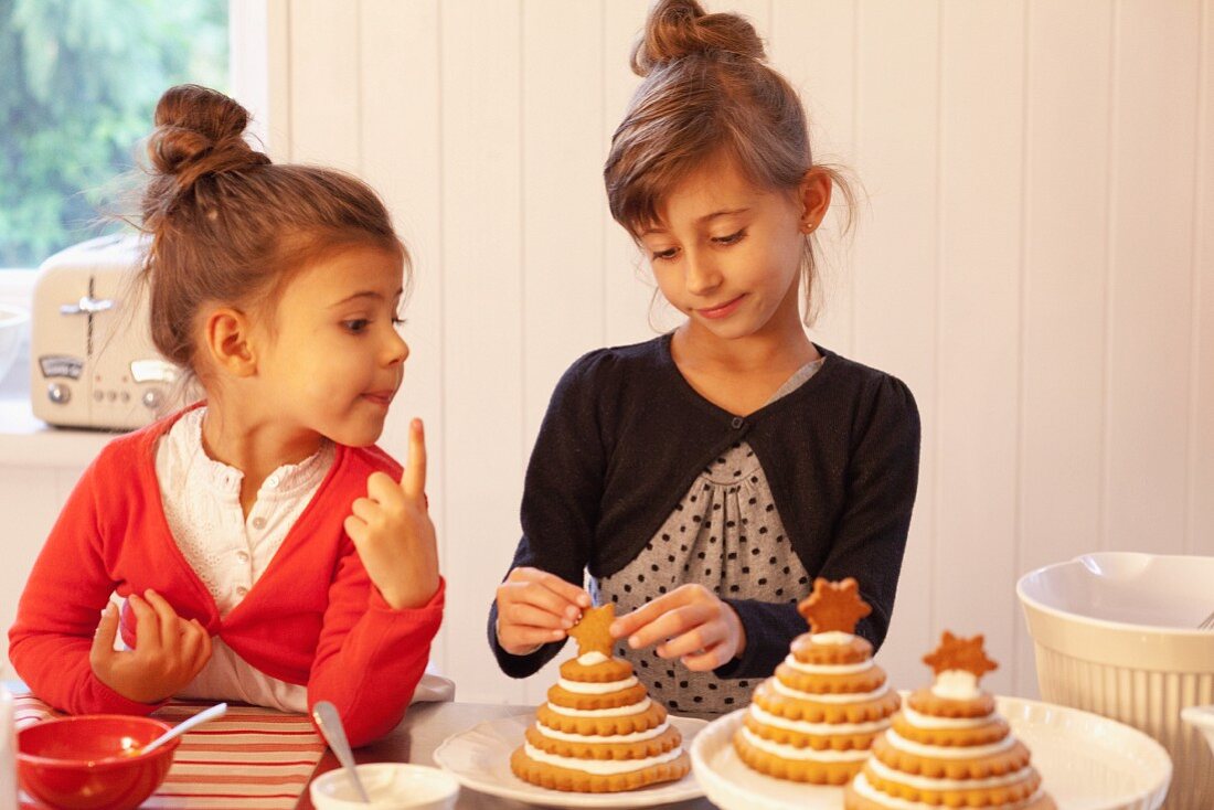 Two girls decorating Christmas trees made from stacked Lebkuchen (spiced soft gingerbread from Germany)