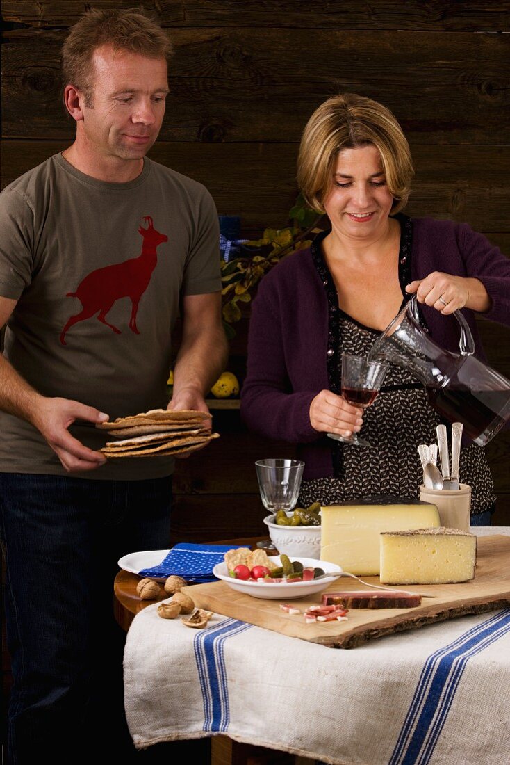 Paar isst rustikale Südtiroler Brotzeit mit Rohschinken, Brot, Nüssen, Käse und Wein