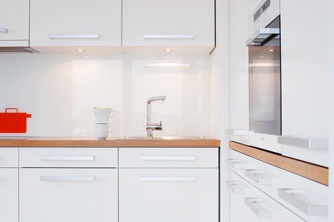 Kitchen with white furnishings, wooden worksurface and fitted cooker