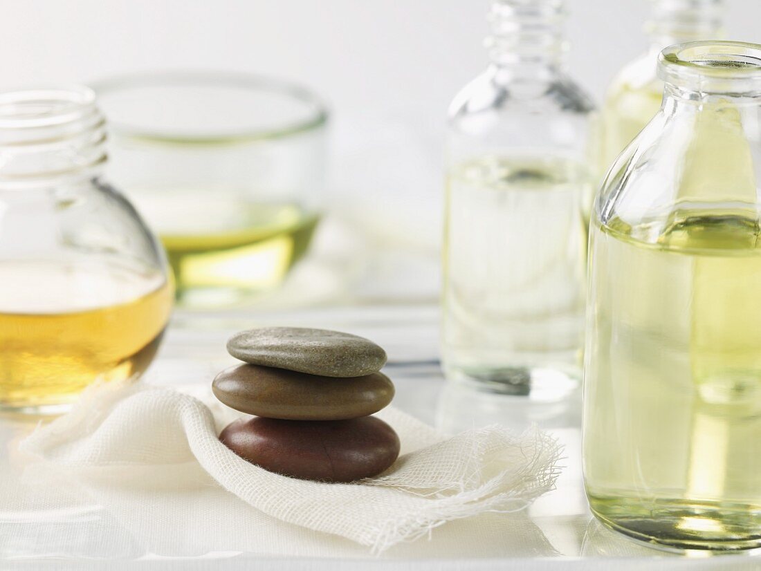 Three stacked spa pebbles and bottles of assorted oils