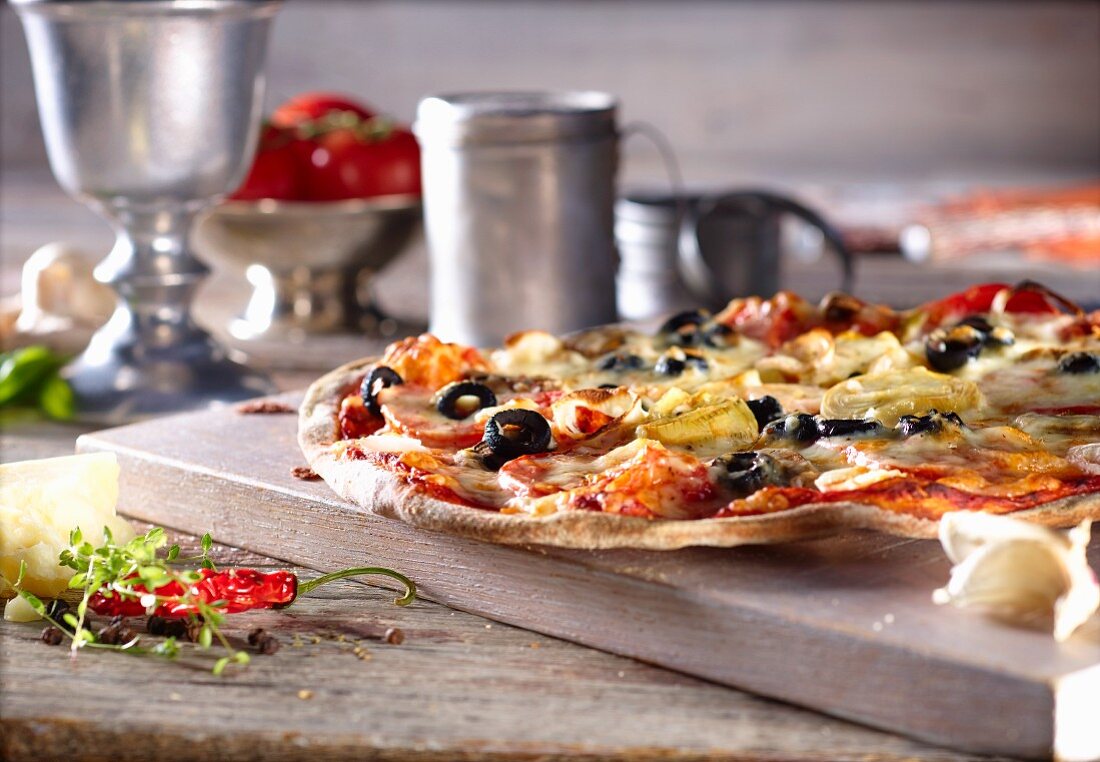 Pizza mit Paprikawurst, schwarzen Oliven und Lauch