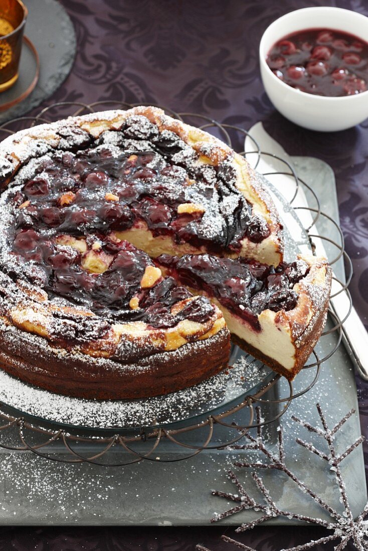 Baked cheesecake with mulled wine cherries, partly sliced, for Christmas