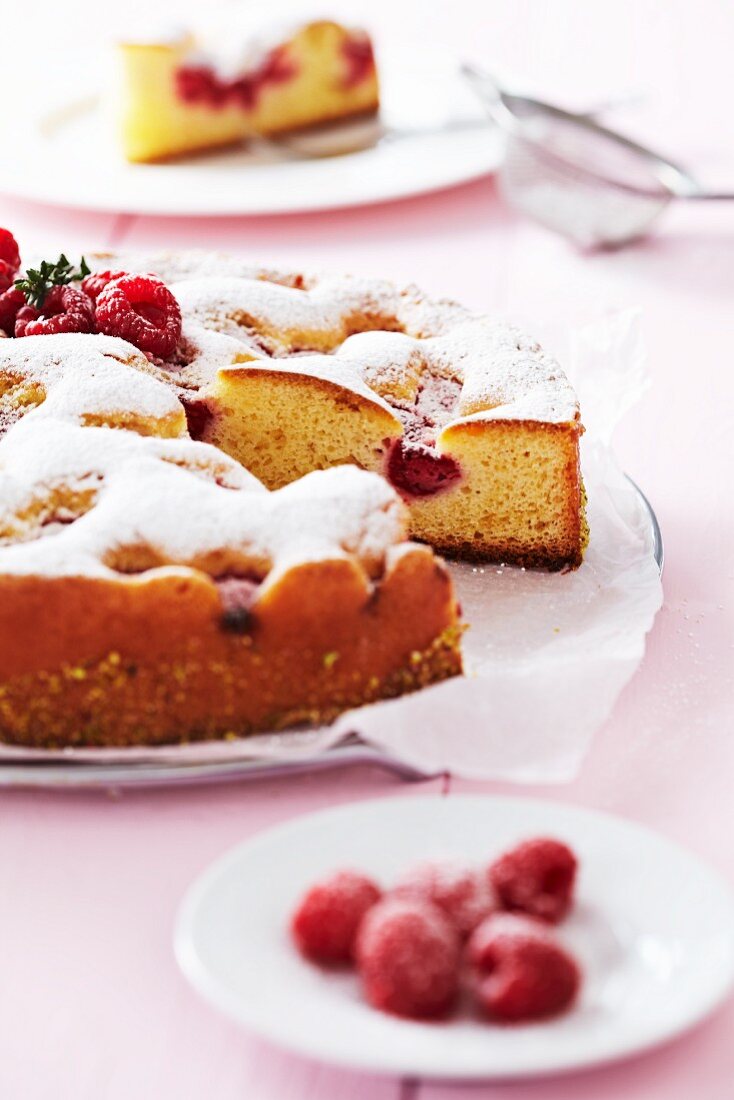 Raspberry cake with icing sugar, partly sliced