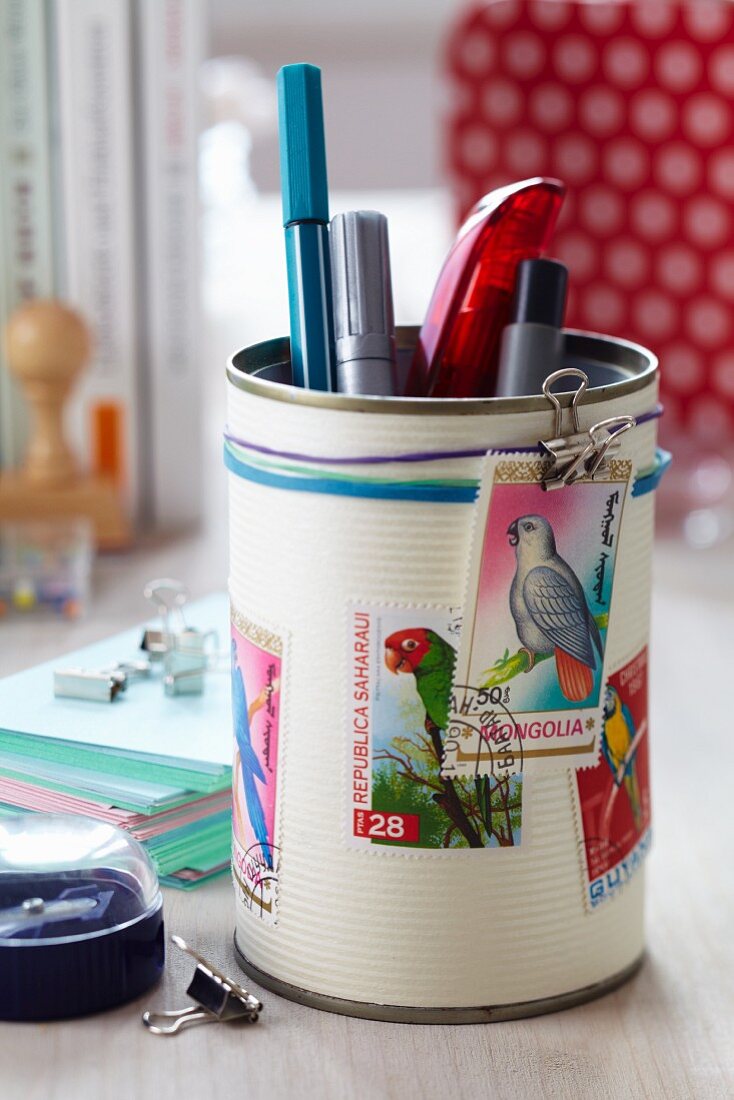 Tin can decorated with postage stamps with bird motifs used as pen holder