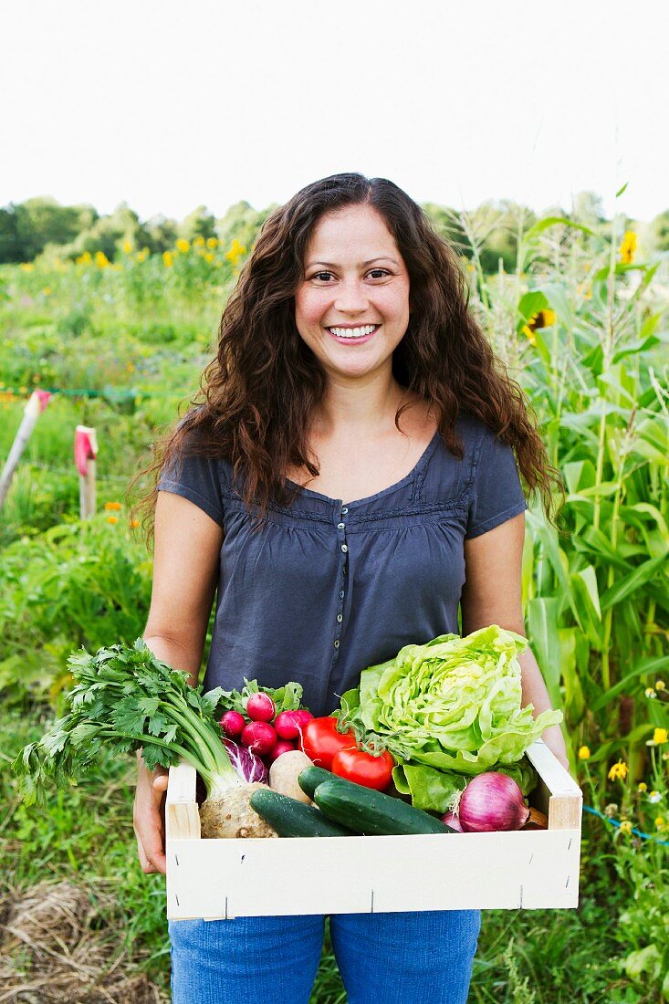 Junge Frau hält Gemüsekiste