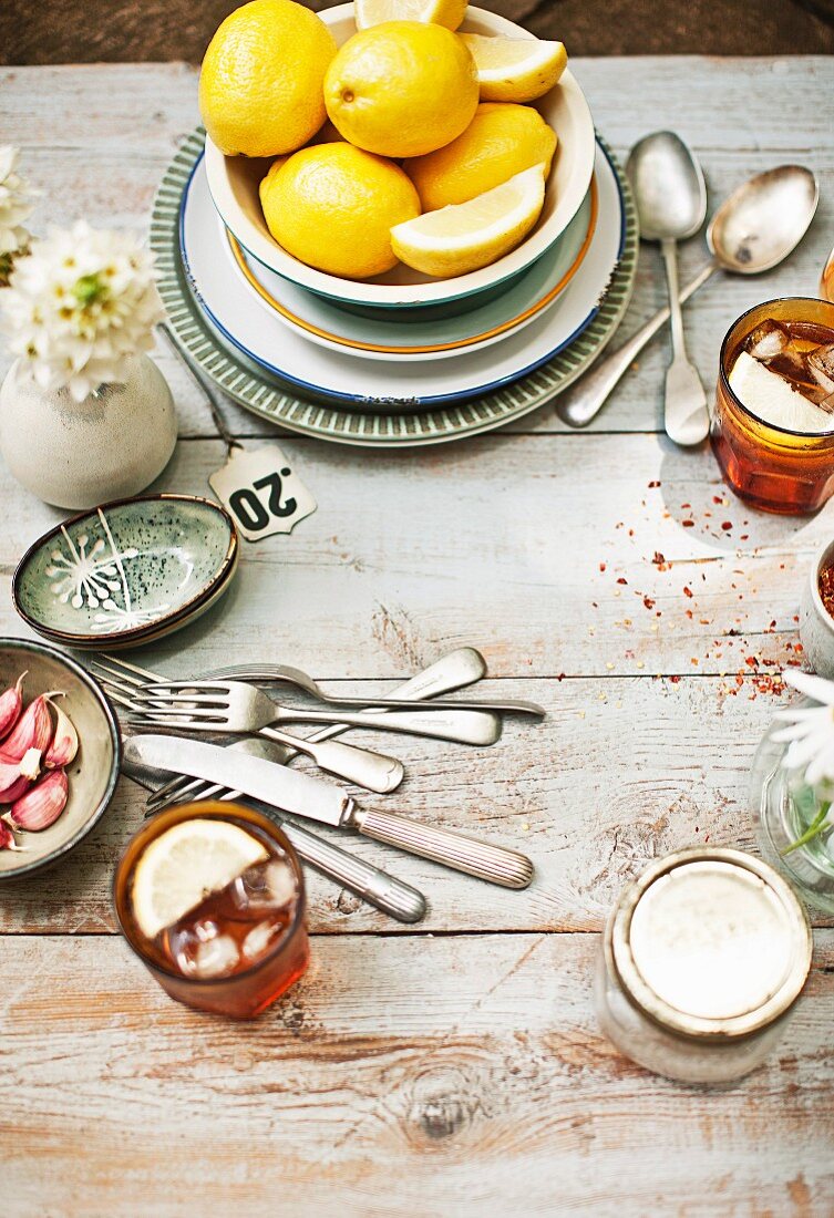 A view onto a wooden table with a bowl of lemons, iced teas and cutlery