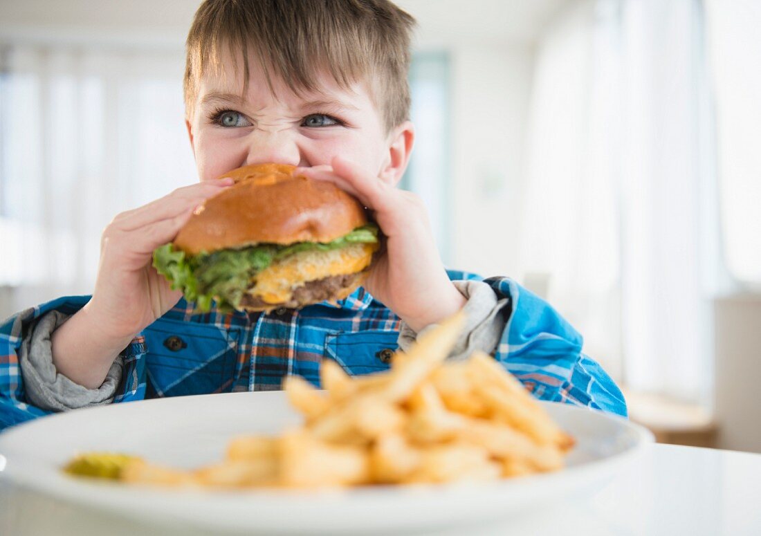 A boy biting into a hamburger