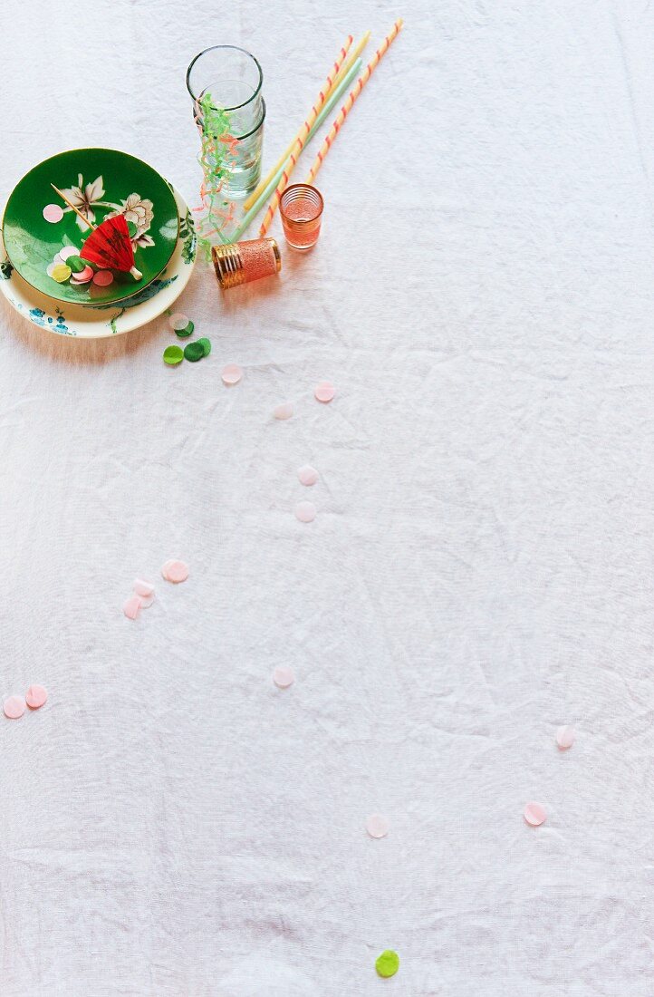 Colourful crockery and glasses with straws, streamers and confetti