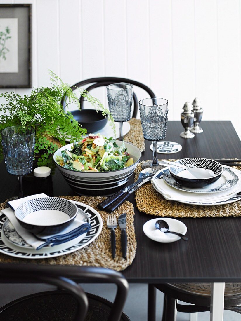 Waldorfsalat mit Schweinefleisch in Schüssel auf schwarz-weiss gedecktem Tisch