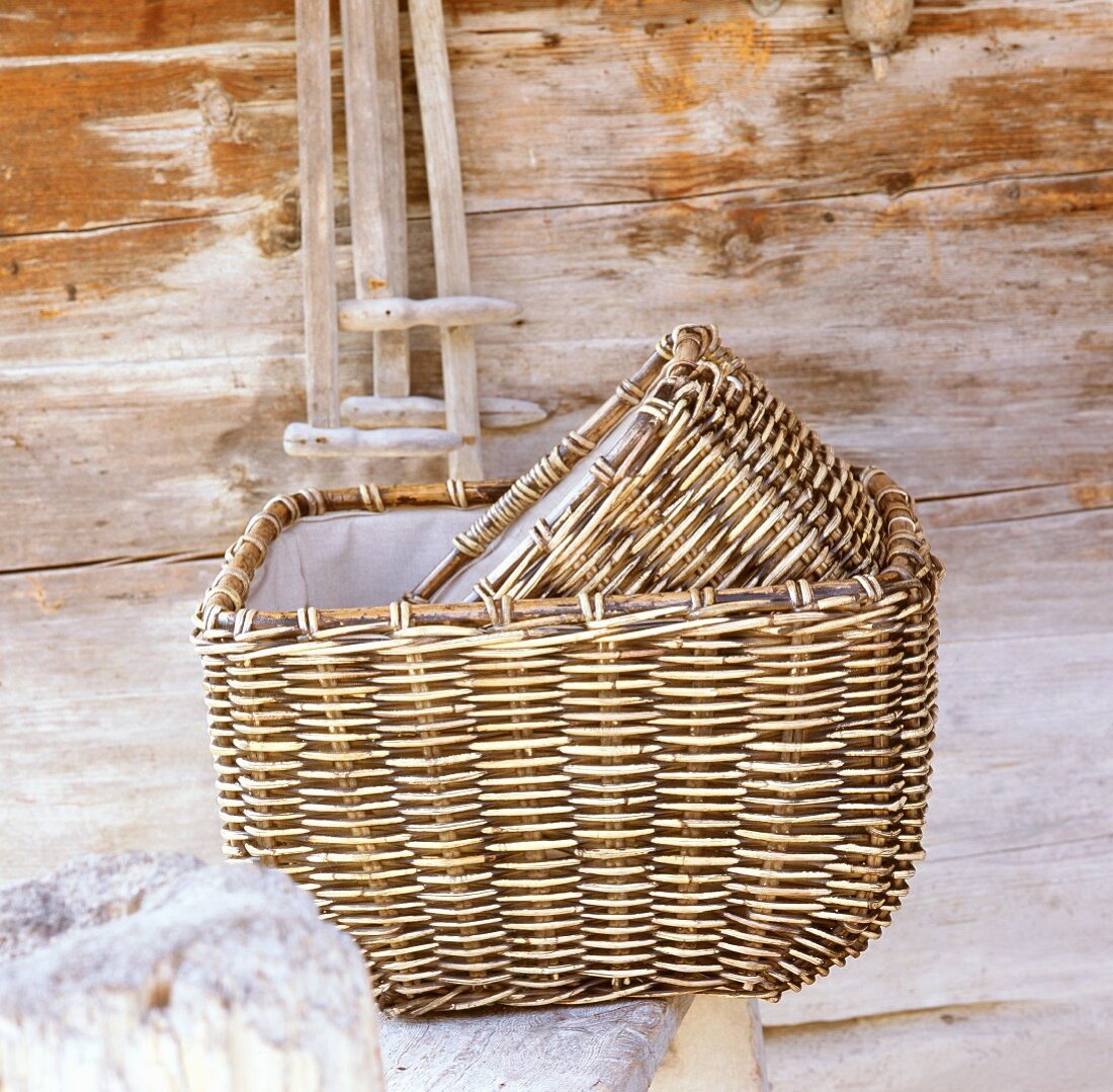 Two hand-woven willow baskets in front of wooden wall
