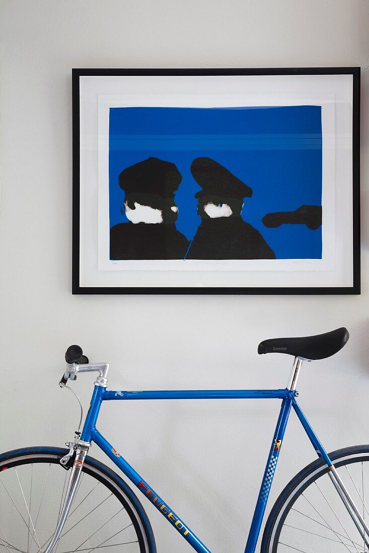 Contemporary blue and black artwork and racing bike in matching colours against white wall