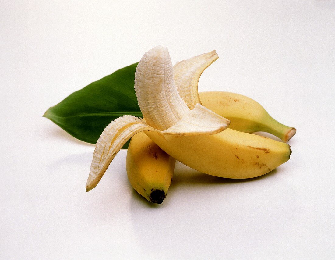 Ungeschälte Banane & geschälte Banane mit Bananenblatt