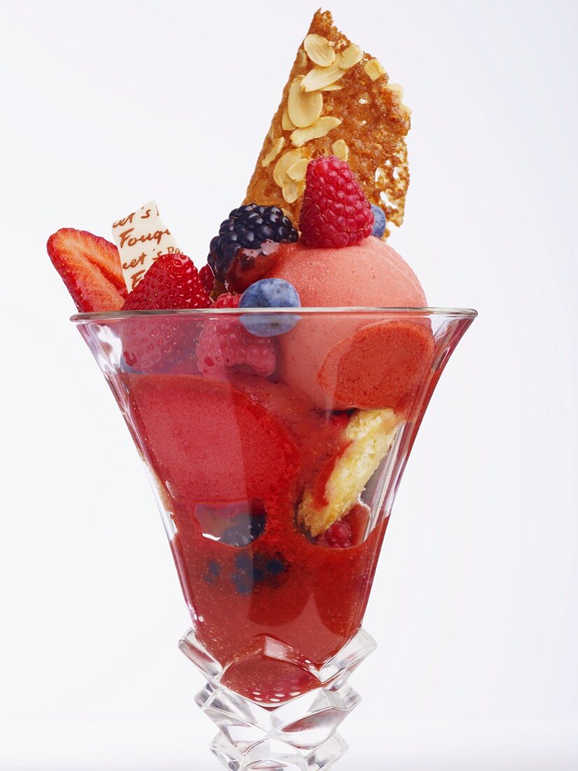 An ice cream sundae with fruit sorbet and fresh berries against a white background