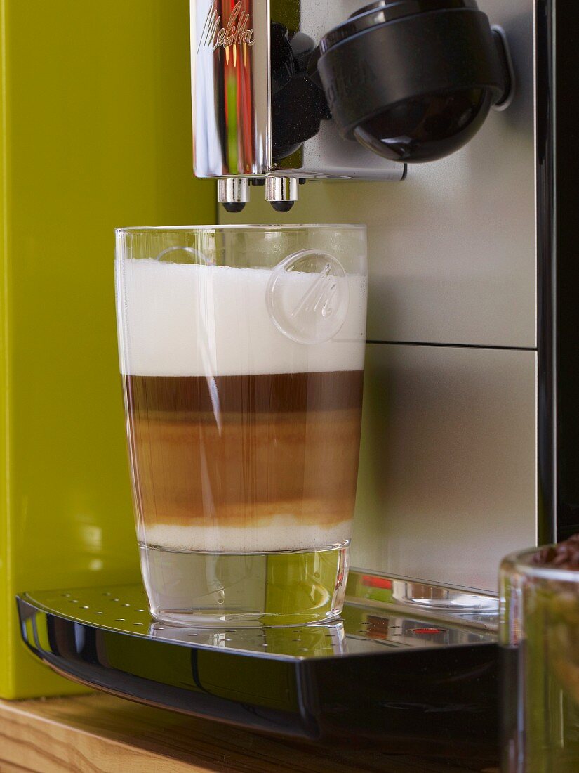 Latte macchiato beneath a coffee maker