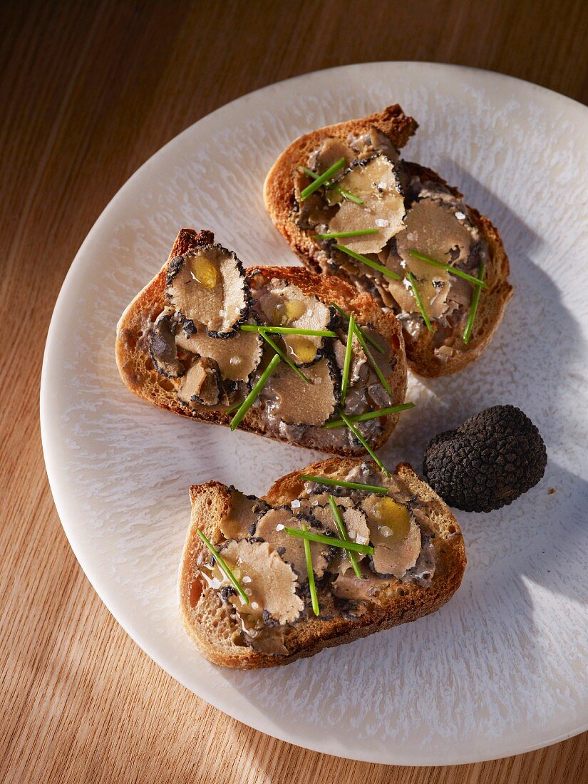Slices of baguette topped with sliced truffles