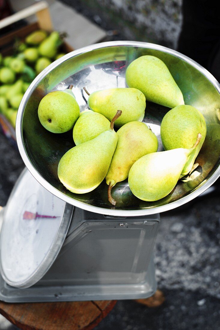 Green pears on weighing scales at the market