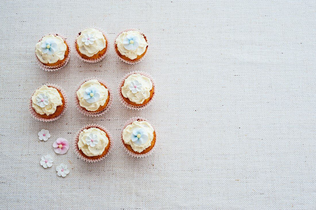 Eight cupcakes decorated with sugar flowers (view from above)