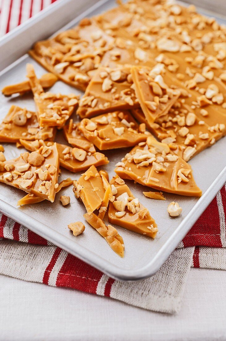 A slab of toffee with cashew nuts on a baking tray