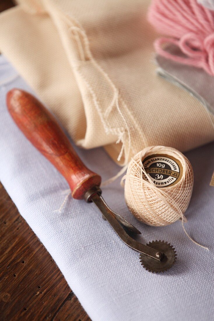 Garnrolle und Schneider-Utensil auf gefaltetem Stoff