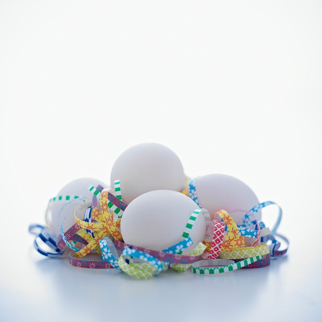 Group of white eggs with curls of shredded paper on a white background