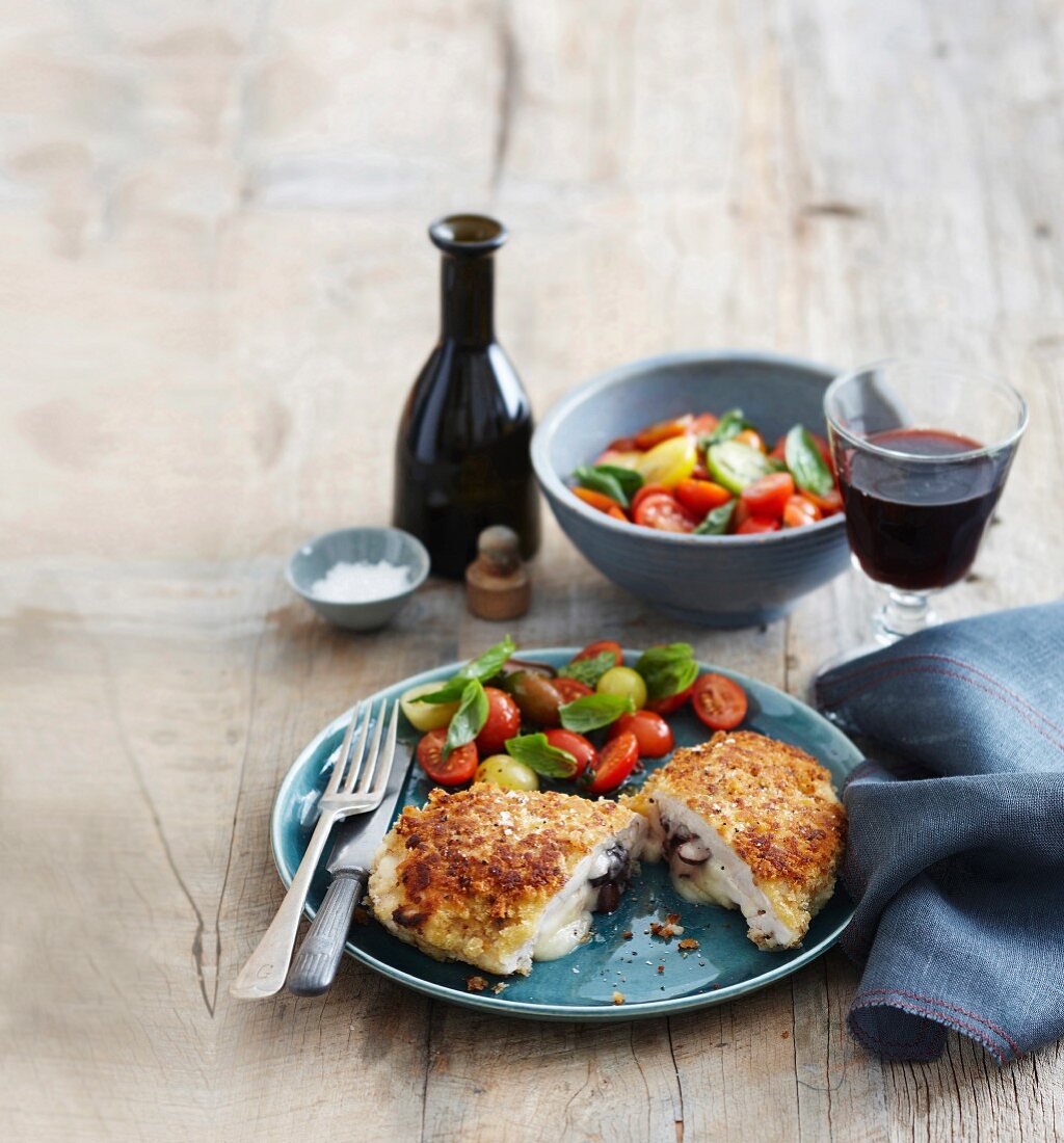 Breaded chicken escalope stuffed with provolone and olives, served with a tomato salad and red wine