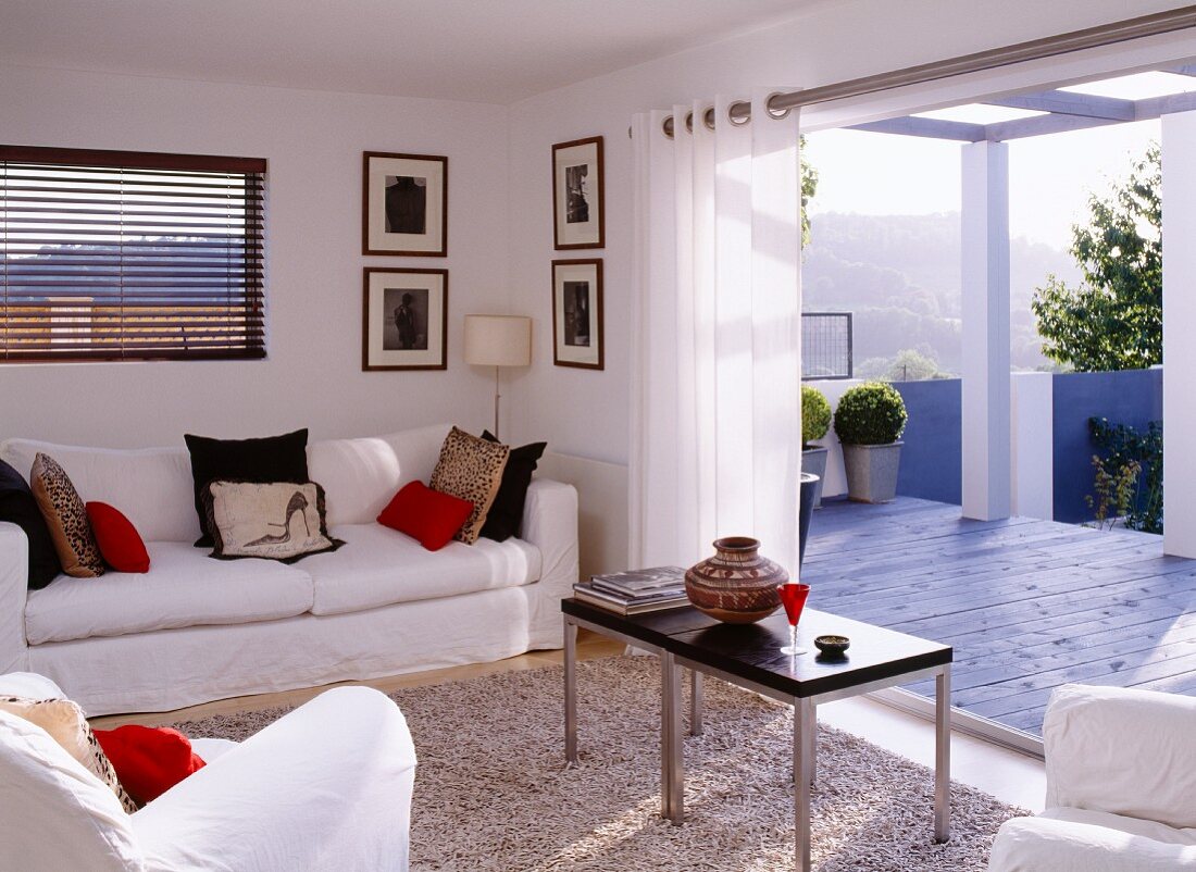 Living room with sofa set in front of open terrace door with view of mountain landscape