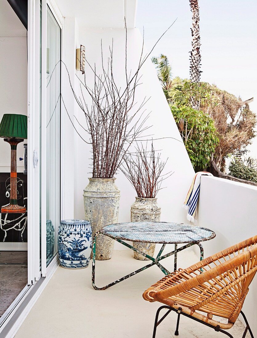 Delicate wicker chair and vintage, metal side table on balcony near beach