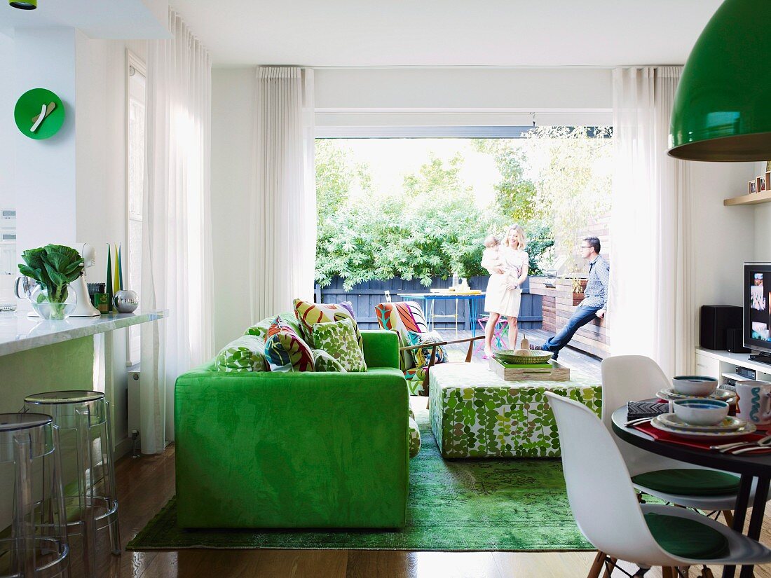 Green accents in open-plan living area with view of young family on terrace