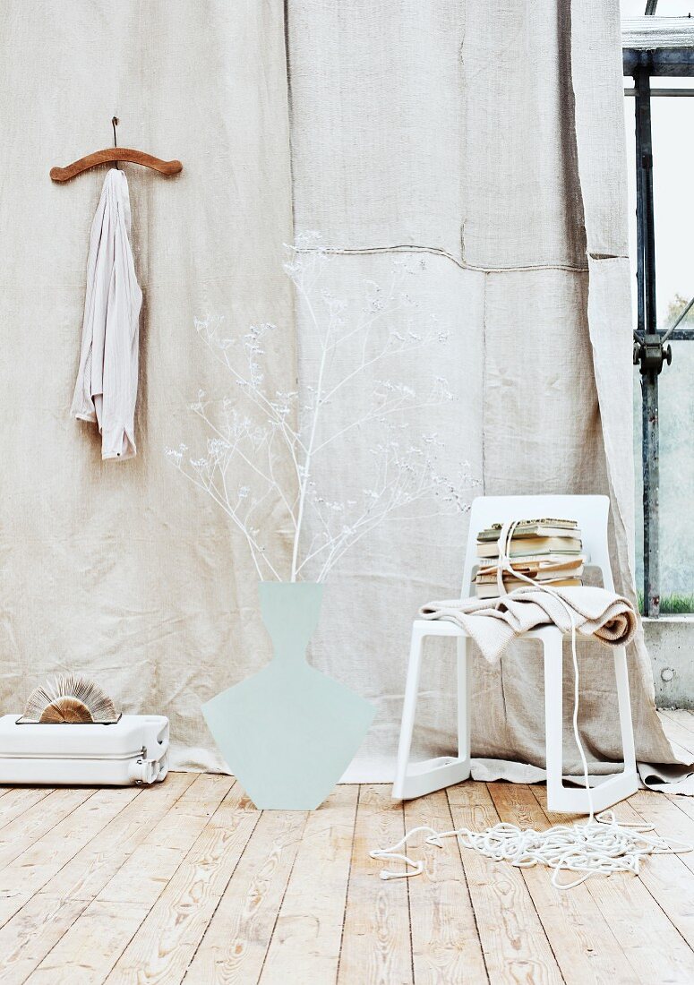 Cardboard vase silhouette and white-painted giant hogweed (Heracleum mantegazzianum) painted white against beige linen backdrop