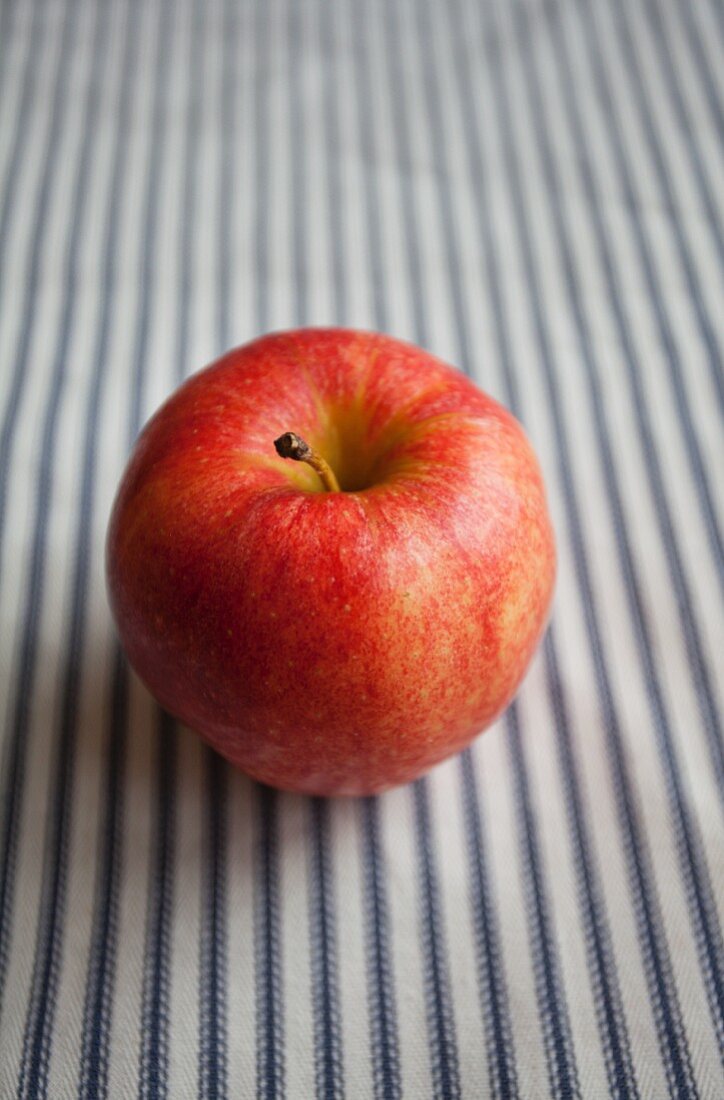 Ein Apfel auf gestreiftem Untergrund