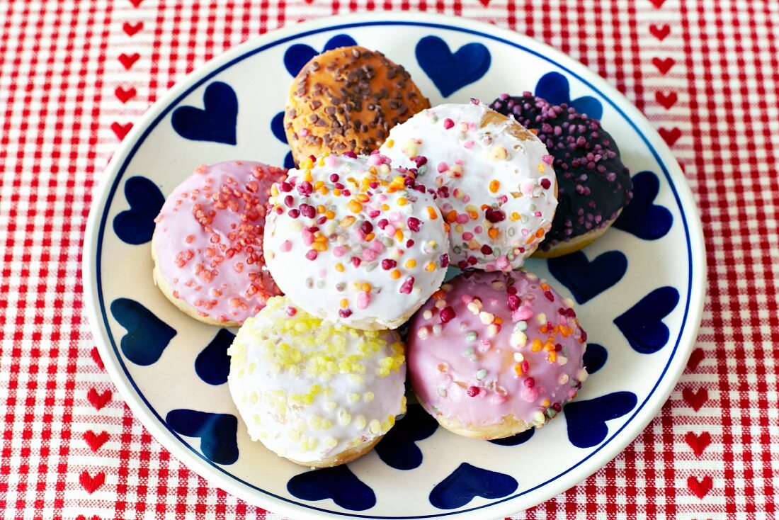 Colourfully decorated doughnuts on a plate with a heart pattern