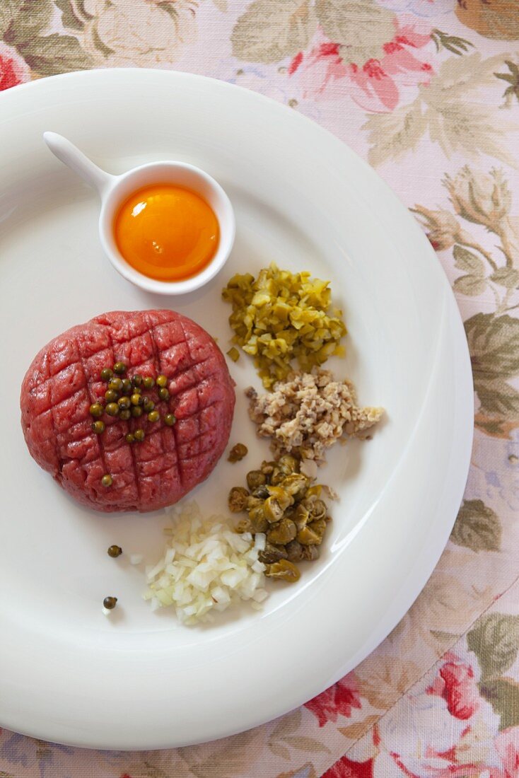 Steak tartare with egg yolk, capers, onions, mushrooms, pickled vegetables and green peppercorns