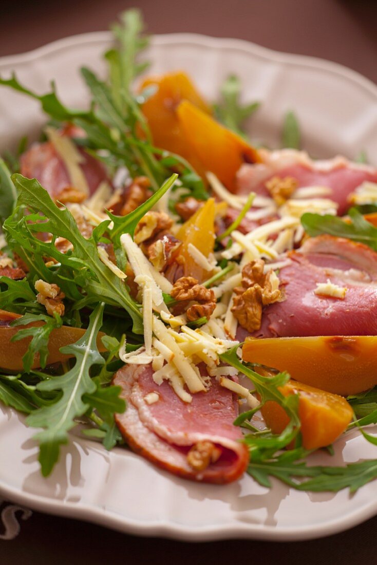 Salat mit gekochtem Schinken, Rucola, Walnüssen, gelben Pflaumen und Käse